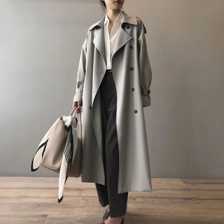 Sage green double-breasted trench coat worn with black tailored pants and a tote
