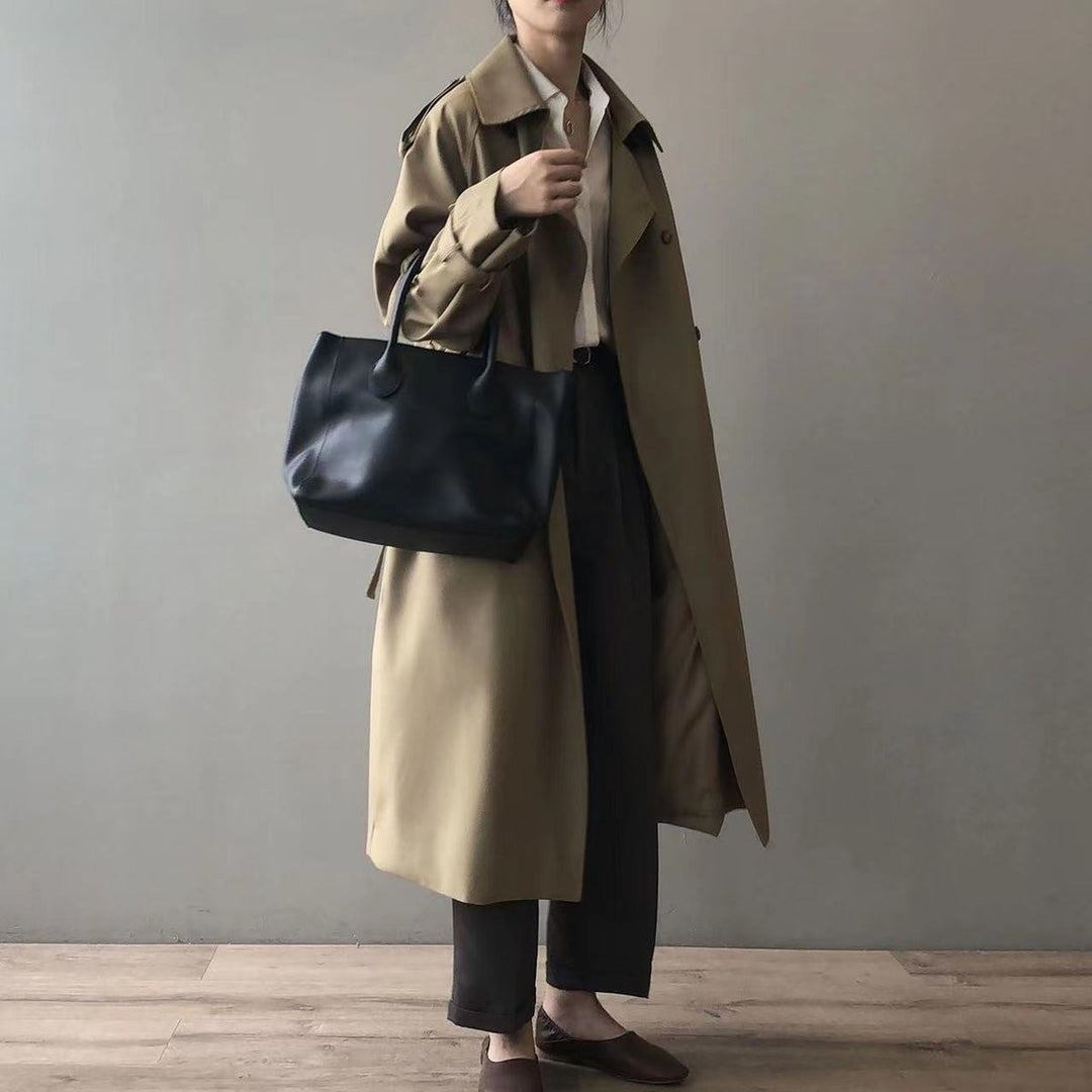 Khaki double-breasted trench coat paired with a black leather tote and cropped trousers