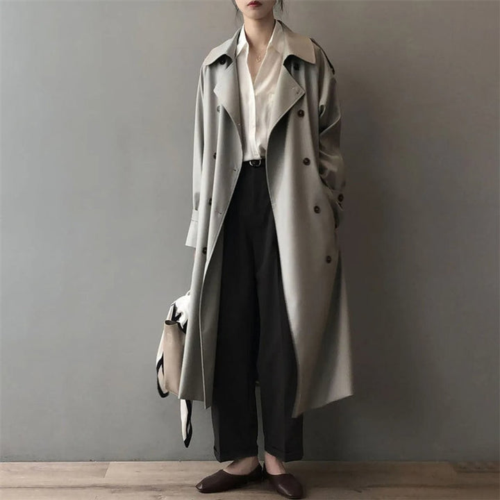 Sage green oversized trench coat with wide lapels styled over a white blouse