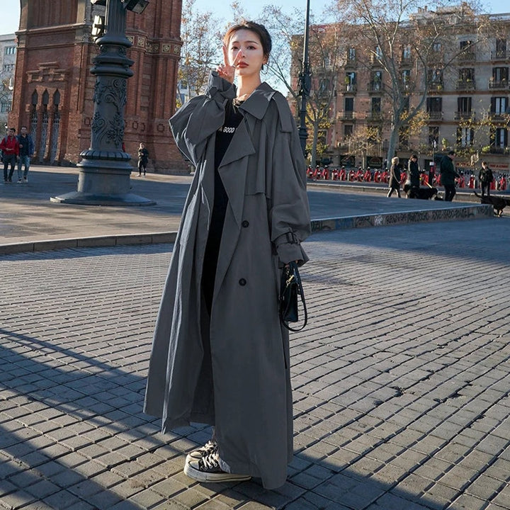 Oversized gray double-breasted trench coat with wide lapel, worn on city street
