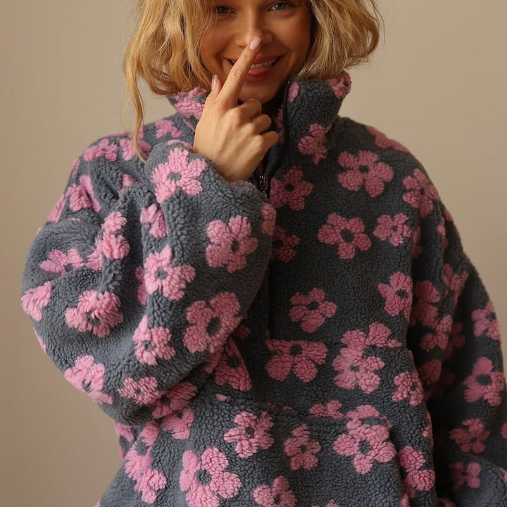 close-up of gray sherpa fleece pullover featuring pink floral pattern and zip collar