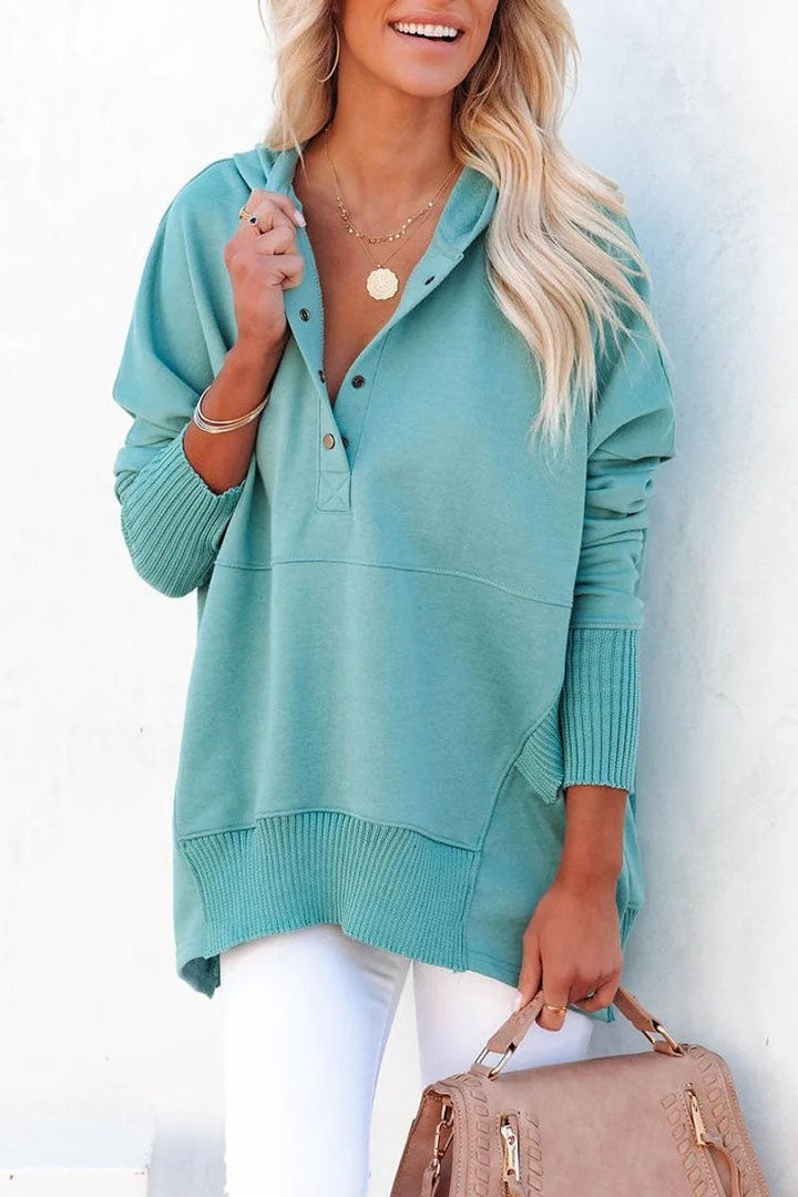 Seafoam green hooded sweatshirt paired with white jeans and a tan handbag