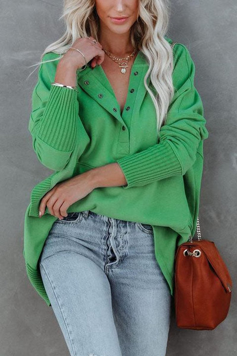 Green hooded sweatshirt close-up showing snap placket and ribbed sleeves
