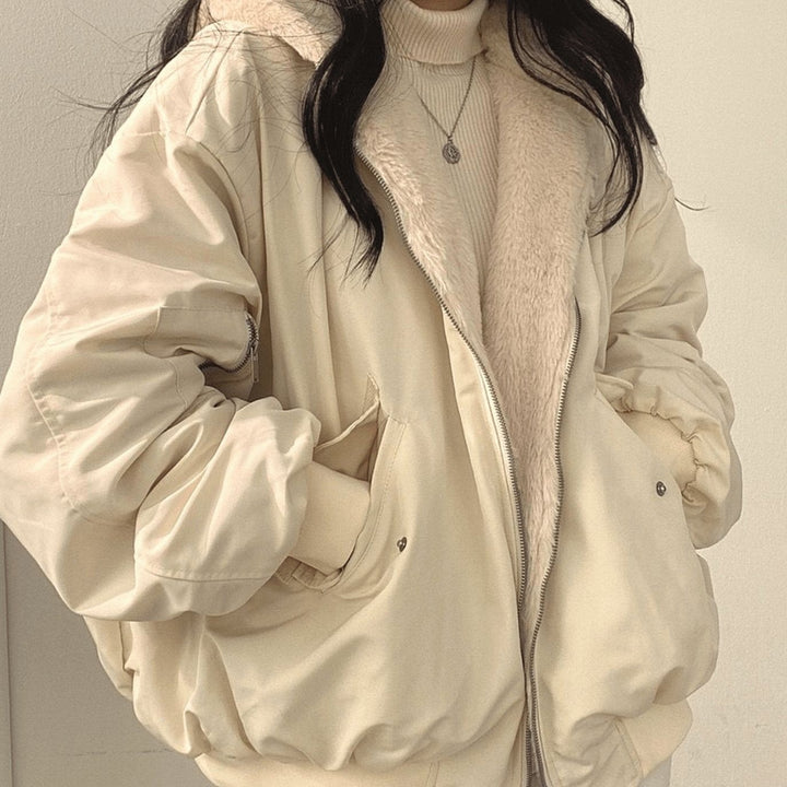 Beige zip-up bomber jacket with hands in front pockets, close-up