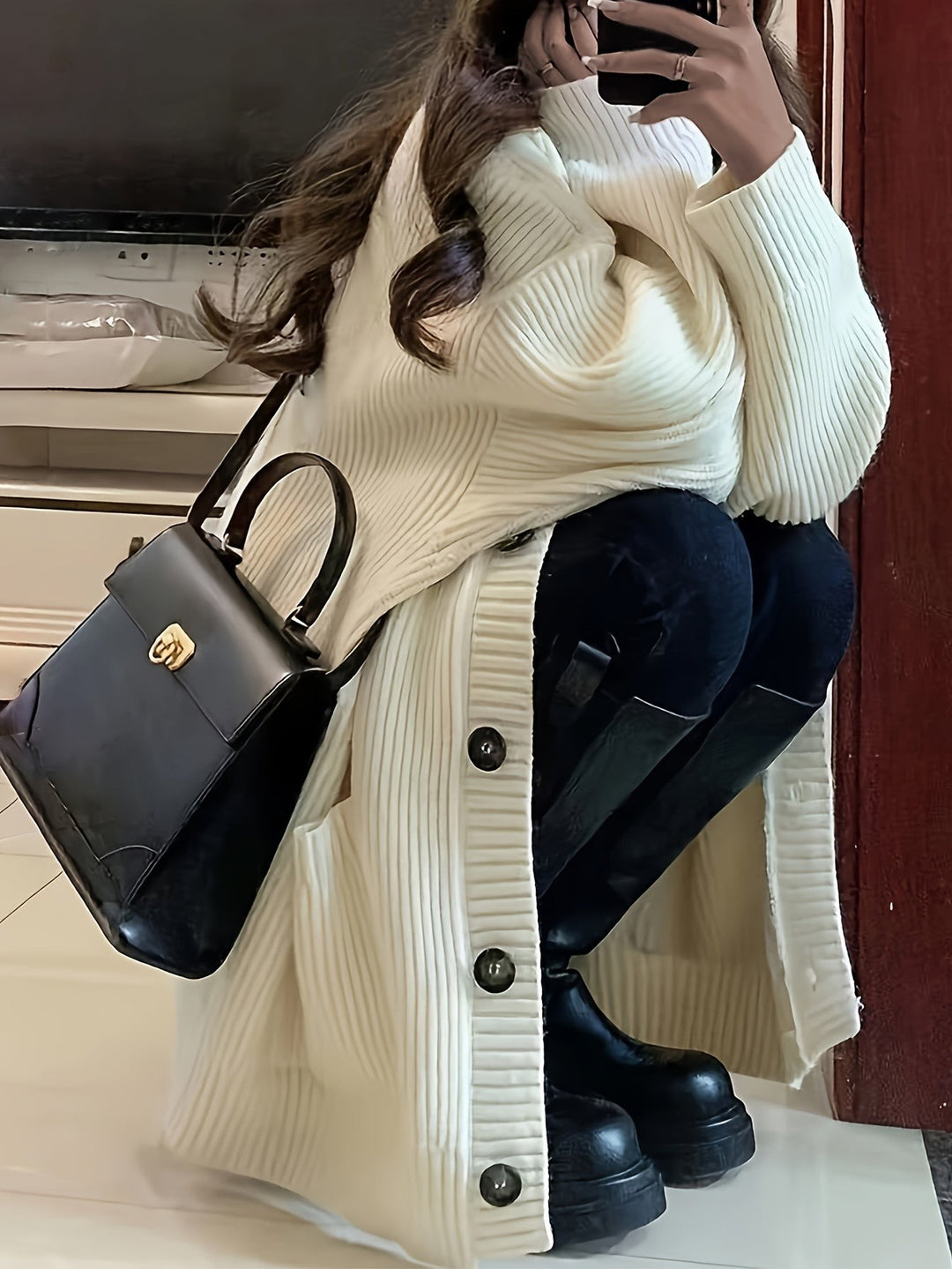 Cream ribbed cardigan worn long over black boots and skinny jeans