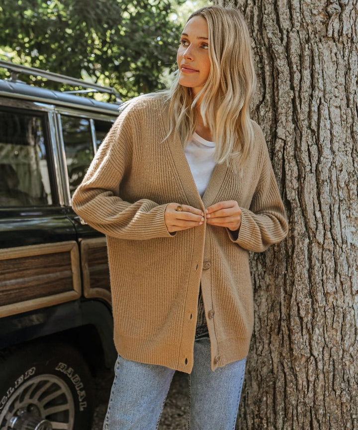 Camel V-neck cardigan buttoned up paired with classic blue jeans
