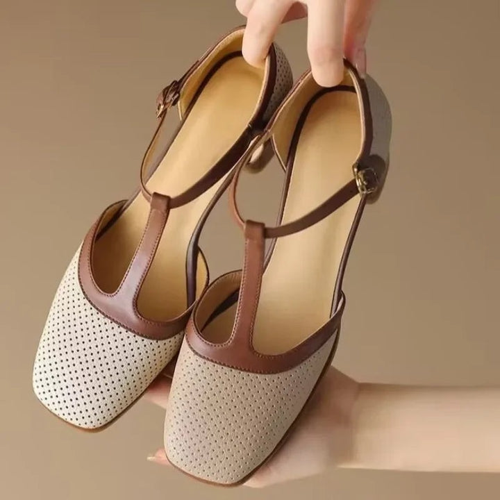 Hand holding beige square toe T-strap mid heel pumps with brown leather straps