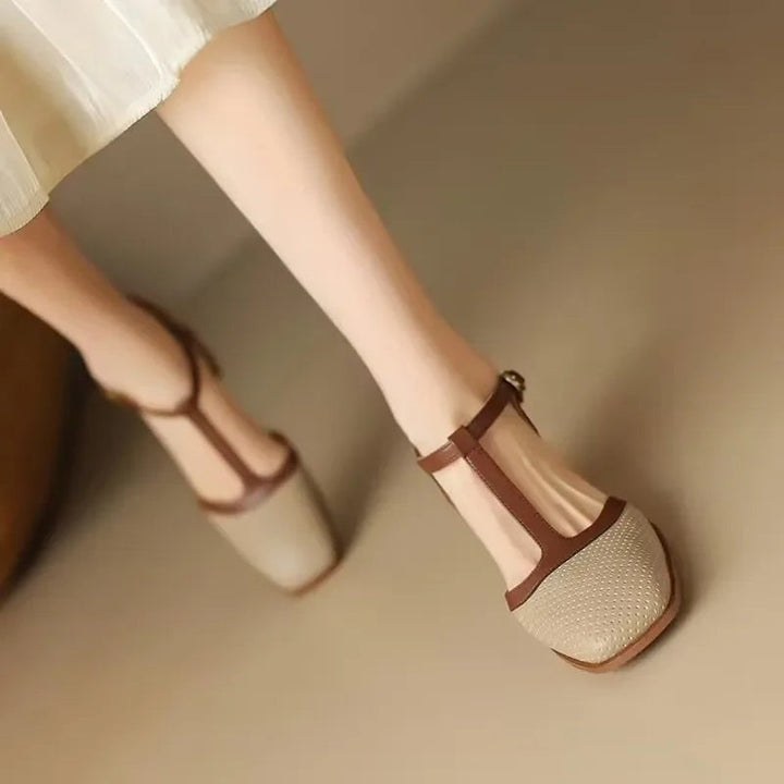 Beige T-strap block heel shoes with brown trim worn while walking