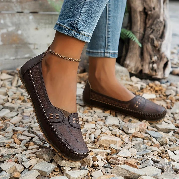 Dark brown perforated loafers paired with denim and ankle chain