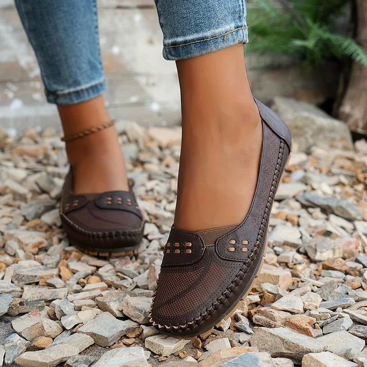 Brown leather flats with laser-cut vamp shown from behind while walking