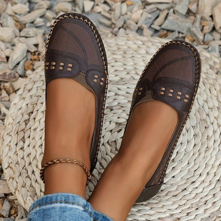 Espresso brown loafers with perforated pattern on rocky outdoor terrain
