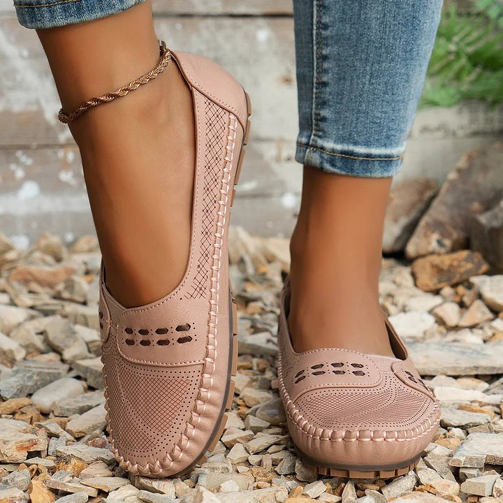 Dark brown slip-on flats with woven texture displayed on straw mat