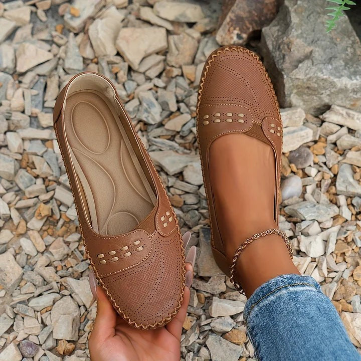 Tan leather slip-on loafers featuring laser-cut detailing and contrast stitching