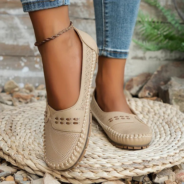 Beige leather loafers worn with rolled cuff jeans on woven mat