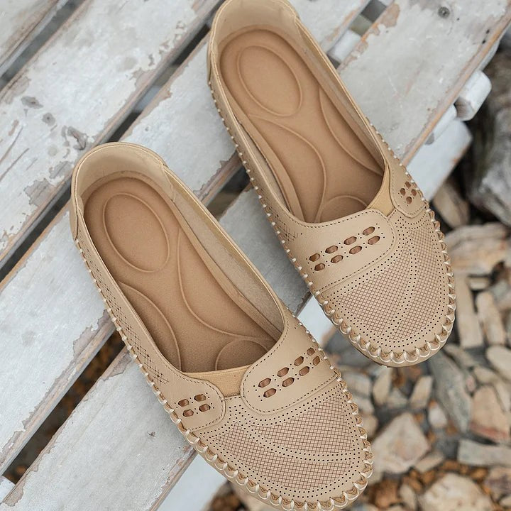 Cream loafers with cutout pattern displayed on rustic wooden slats