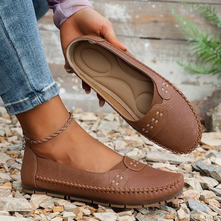 Hand holding tan loafer showing cushioned orthopedic insole design