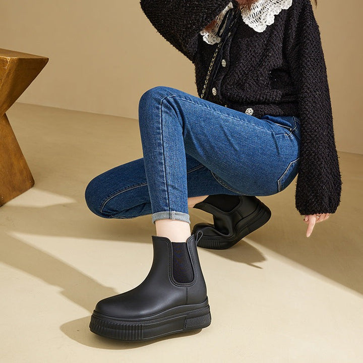 Model crouching in black platform Chelsea boots with cuffed denim jeans