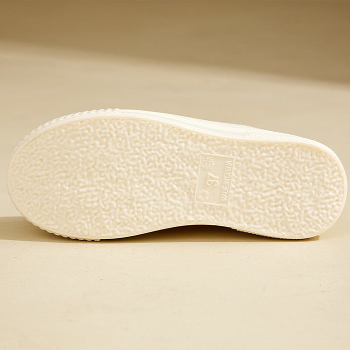 Bottom view of ivory rubber boot sole with textured tread pattern