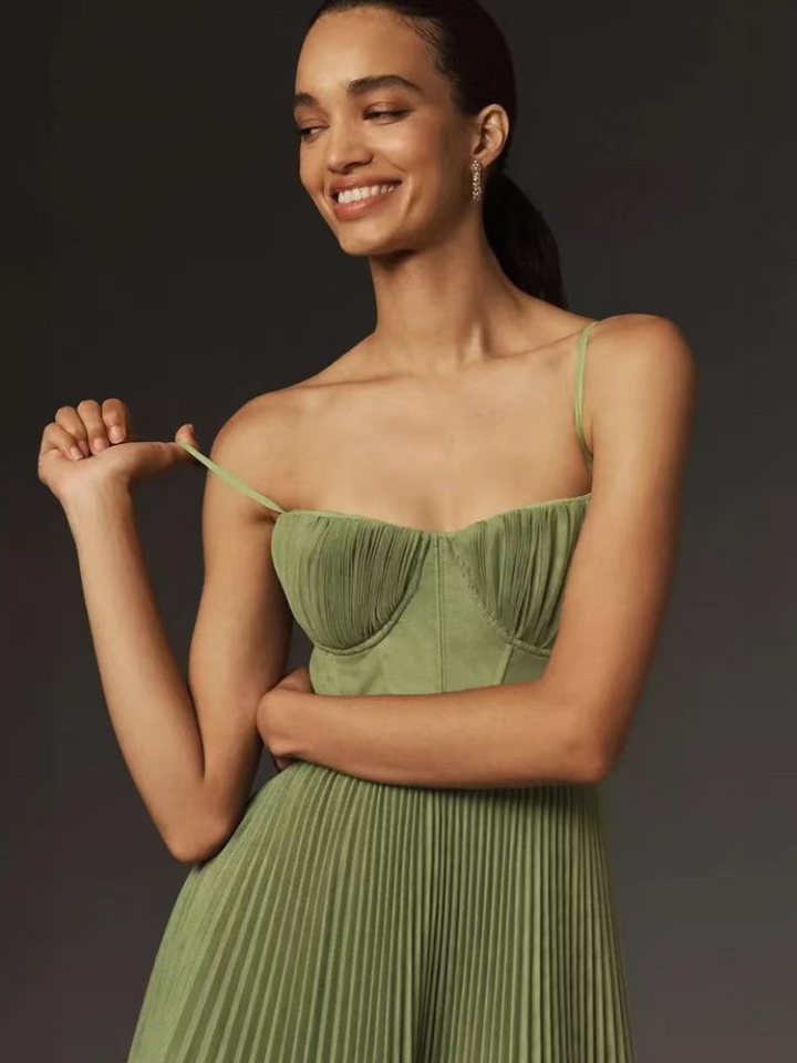 Smiling model in sage green sweetheart-neck dress adjusting thin shoulder strap