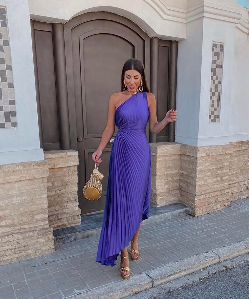 purple one-shoulder pleated midi dress with asymmetric hem and gold sandals