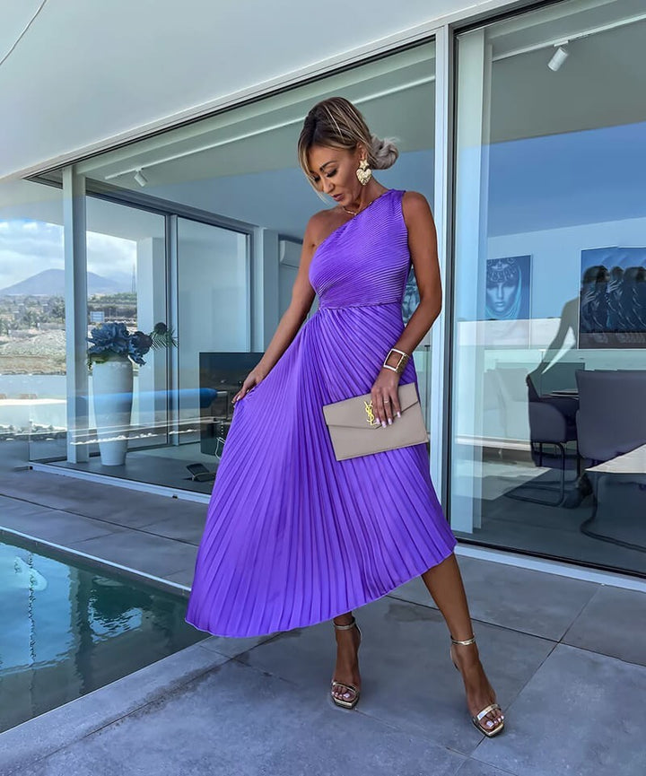 asymmetric purple pleated dress paired with a taupe envelope clutch