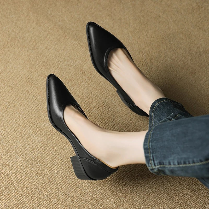 Black pointed-toe block heel pumps worn with rolled denim jeans