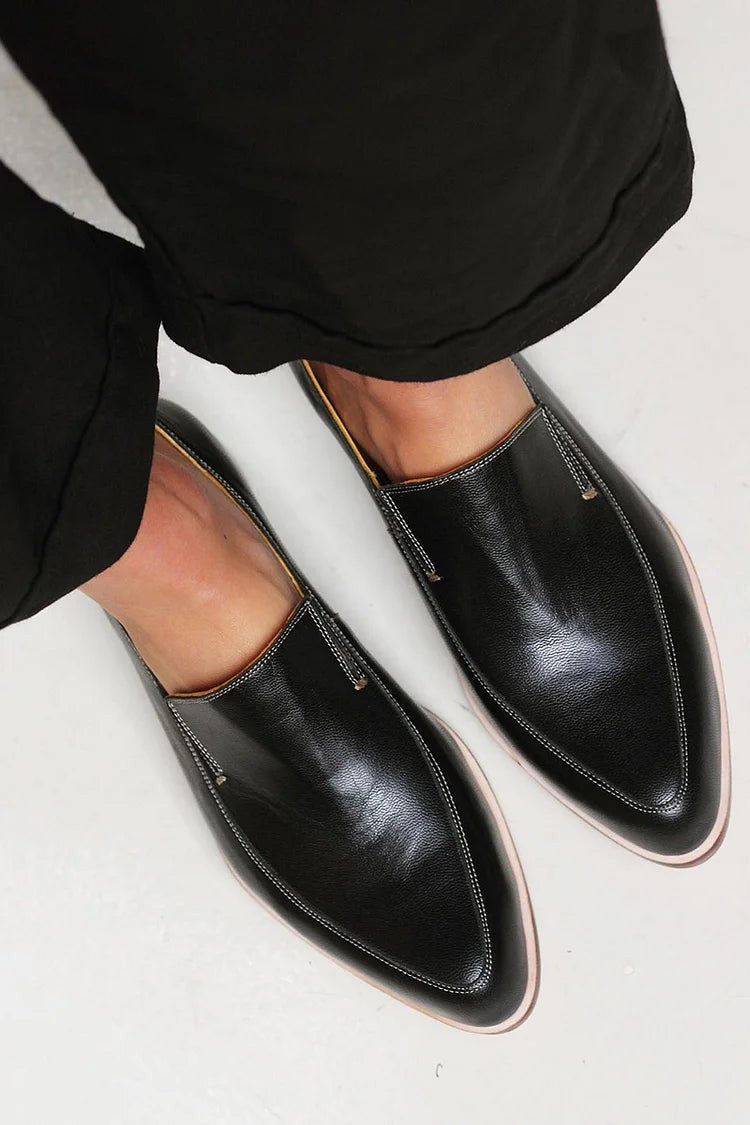 Overhead view of black leather loafers worn with cropped black trousers