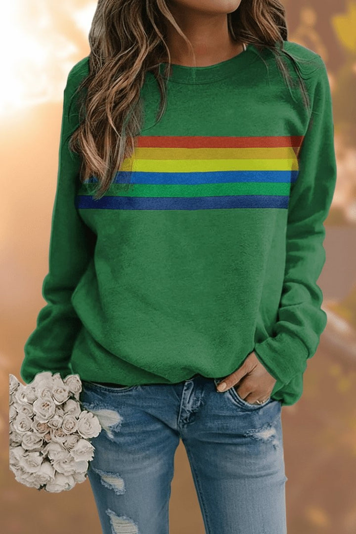 Green crewneck pullover sweatshirt featuring rainbow stripe detail, worn with ripped jeans