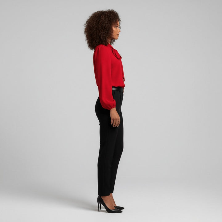 side profile of red tie-neck blouse tucked into black high-waisted pants