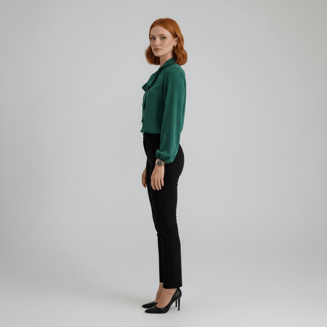 side view of green bow-tie blouse with relaxed fit and black tapered pants