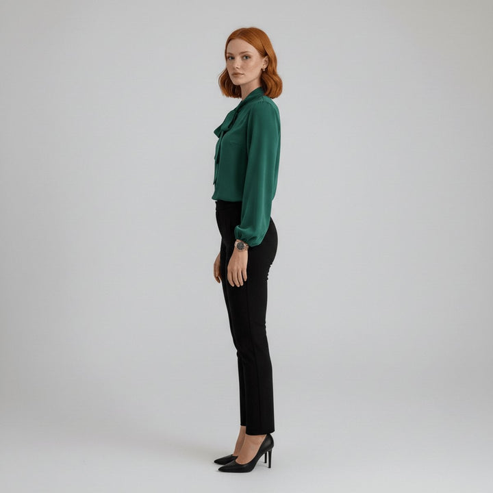 side view of green bow-tie blouse with relaxed fit and black tapered pants