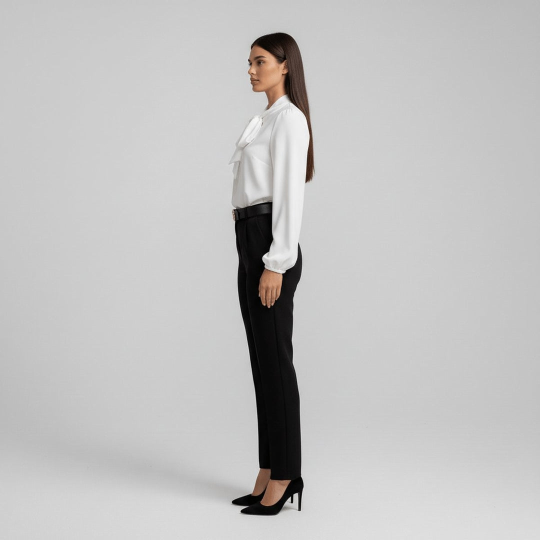 side angle of white bow-blouse tucked into black high-waisted pants