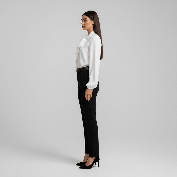 side angle of white bow-blouse tucked into black high-waisted pants