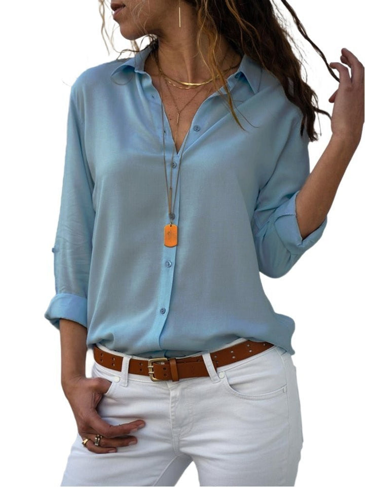 light blue button-down blouse with rolled sleeves and layered gold necklace