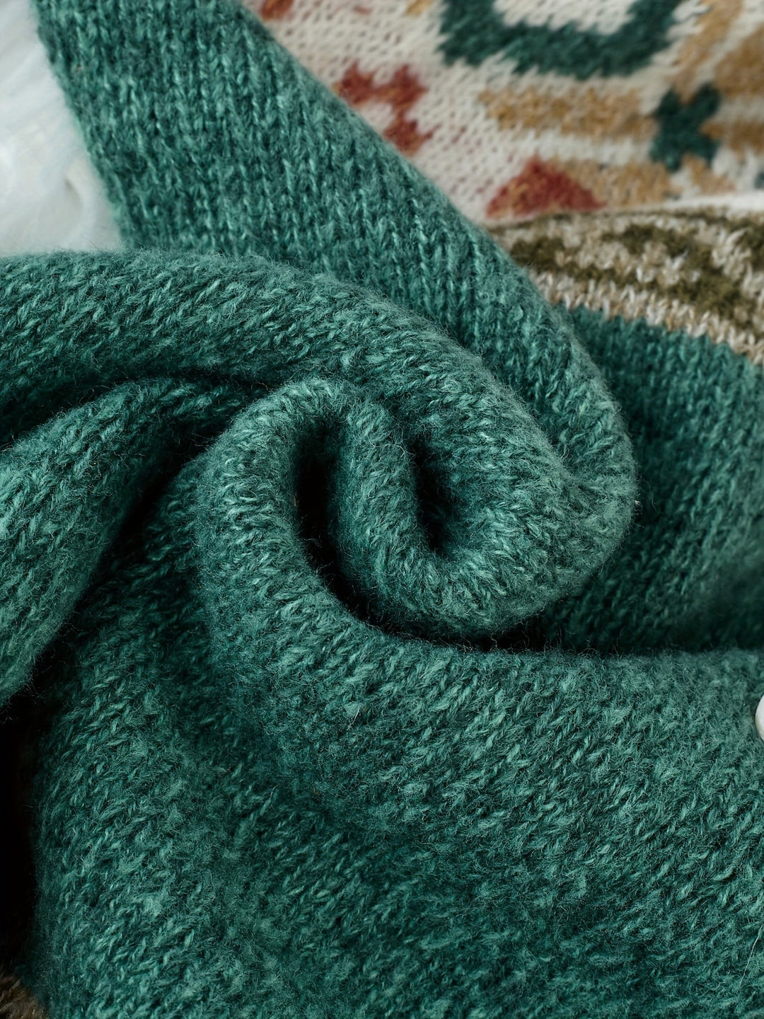 Folded green knit fabric texture detail on patterned cardigan