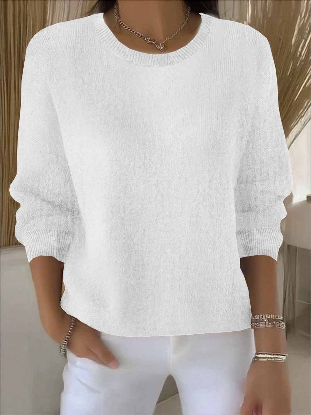 White knit sweater featuring ribbed round neck and relaxed long sleeves