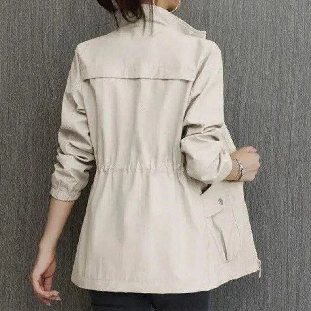 Back view of beige zip-up jacket showing stand collar and elastic cuffs