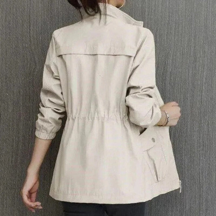 Back view of beige zip-up jacket showing stand collar and elastic cuffs