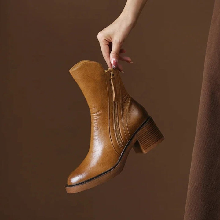 Camel leather ankle boot with block heel held up by hand