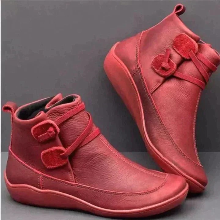 Red leather ankle boots featuring buckle strap and low wedge sole