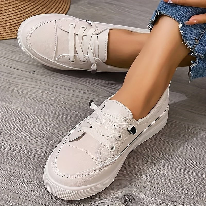White leather lace-up sneakers with cushioned platform sole, worn with jeans
