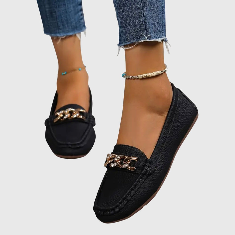 black slip-on loafer flats featuring gold chain and crystal accent