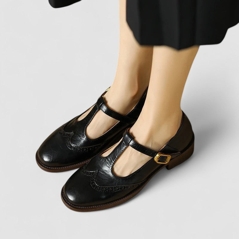 black leather Mary Jane shoes featuring T-strap buckle and perforated brogue toe