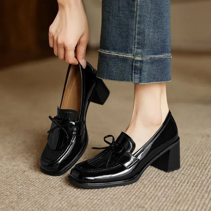 black patent leather tassel loafer pumps with block heel, worn with jeans