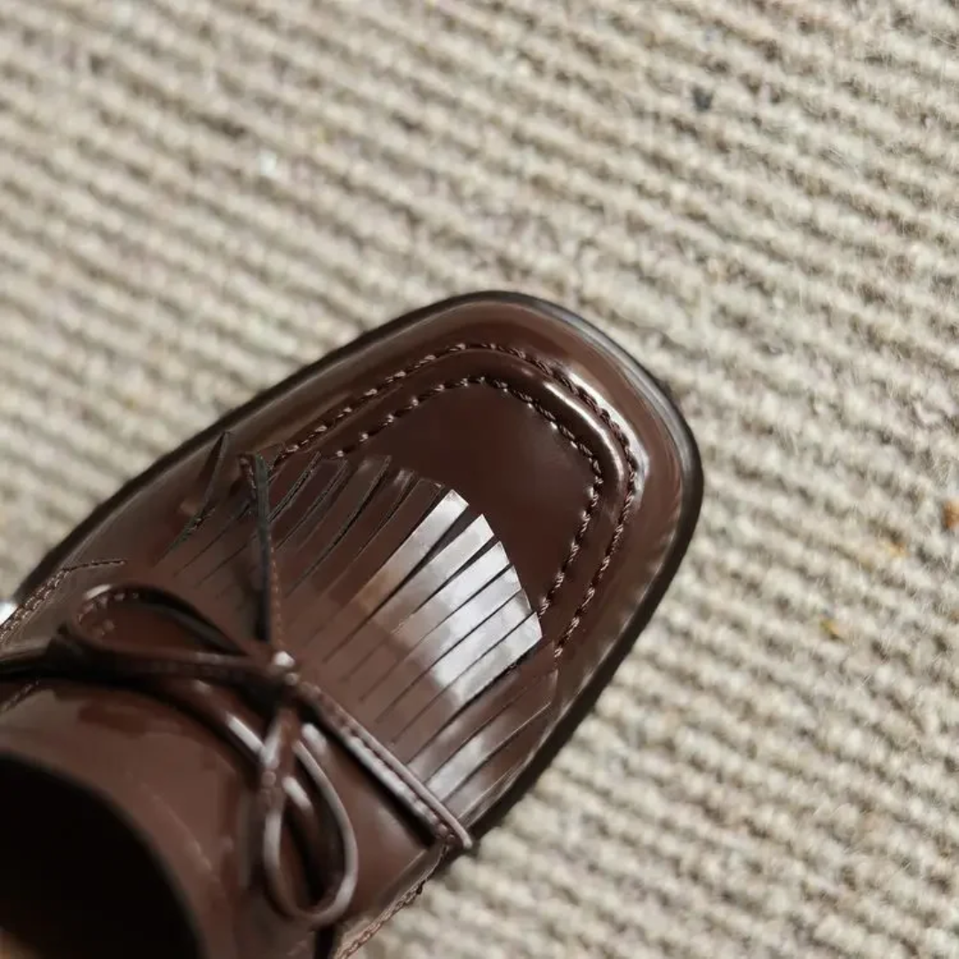 close-up of stacked wooden block heel on brown patent loafer pump