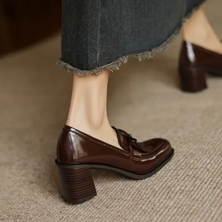 front view of brown tassel loafer pumps on textured carpet flooring