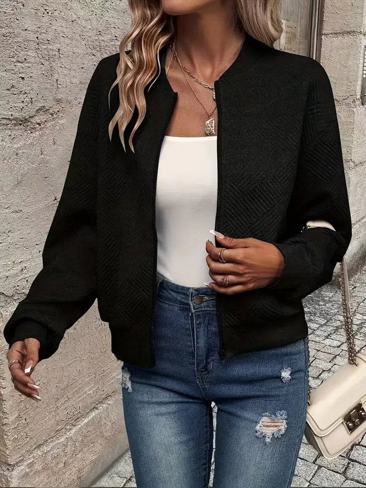 Black quilted cropped bomber jacket worn over white tank top