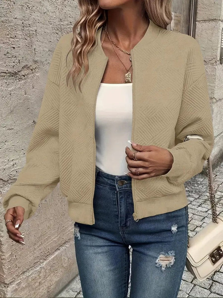 Beige textured zip-up bomber jacket styled with distressed jeans