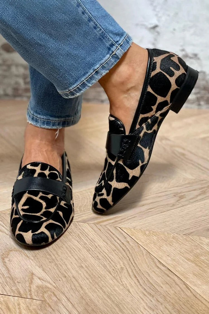 Giraffe-print calf hair loafers with black leather penny strap detail, worn with cropped jeans