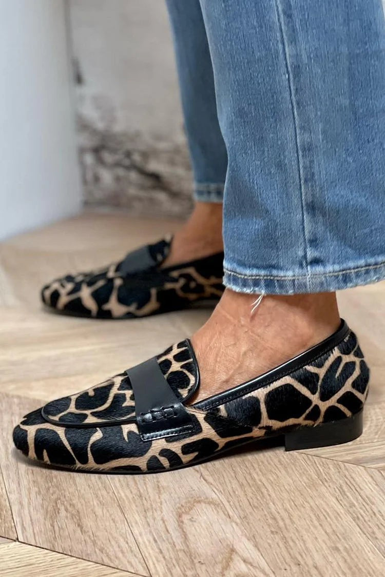 Side view of giraffe-print loafers with black leather collar and slip-on design